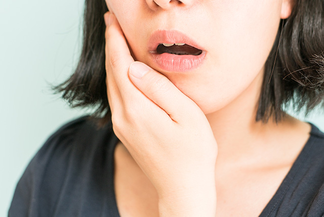 奥歯を痛がる女性の口元