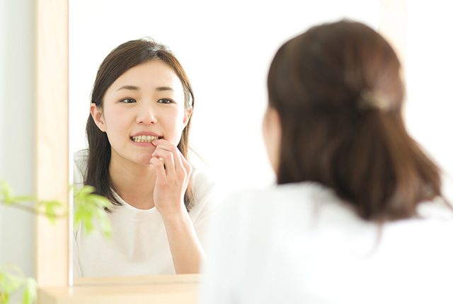 口元を気にして鏡を見る女性